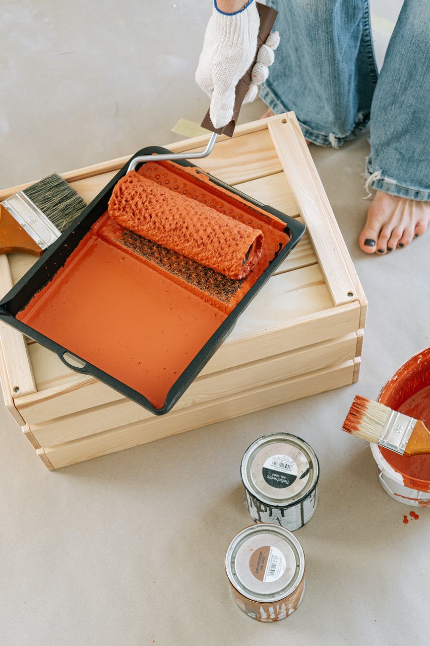 close up shot of a person holding a paint roller with orange paint