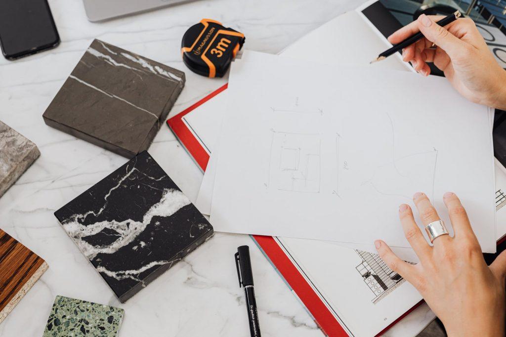 a person drawing beside tile samples