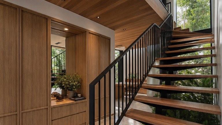 Floating timber stair at the Bangi house over a bed of ferns and black pebbles