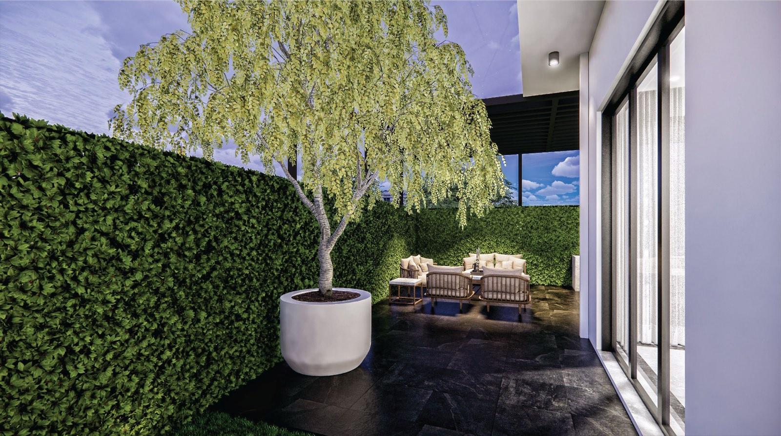 Side courtyard of the Johor Bahru residence with a potted tree, hedge walls and rattan seating on dark stone paving
