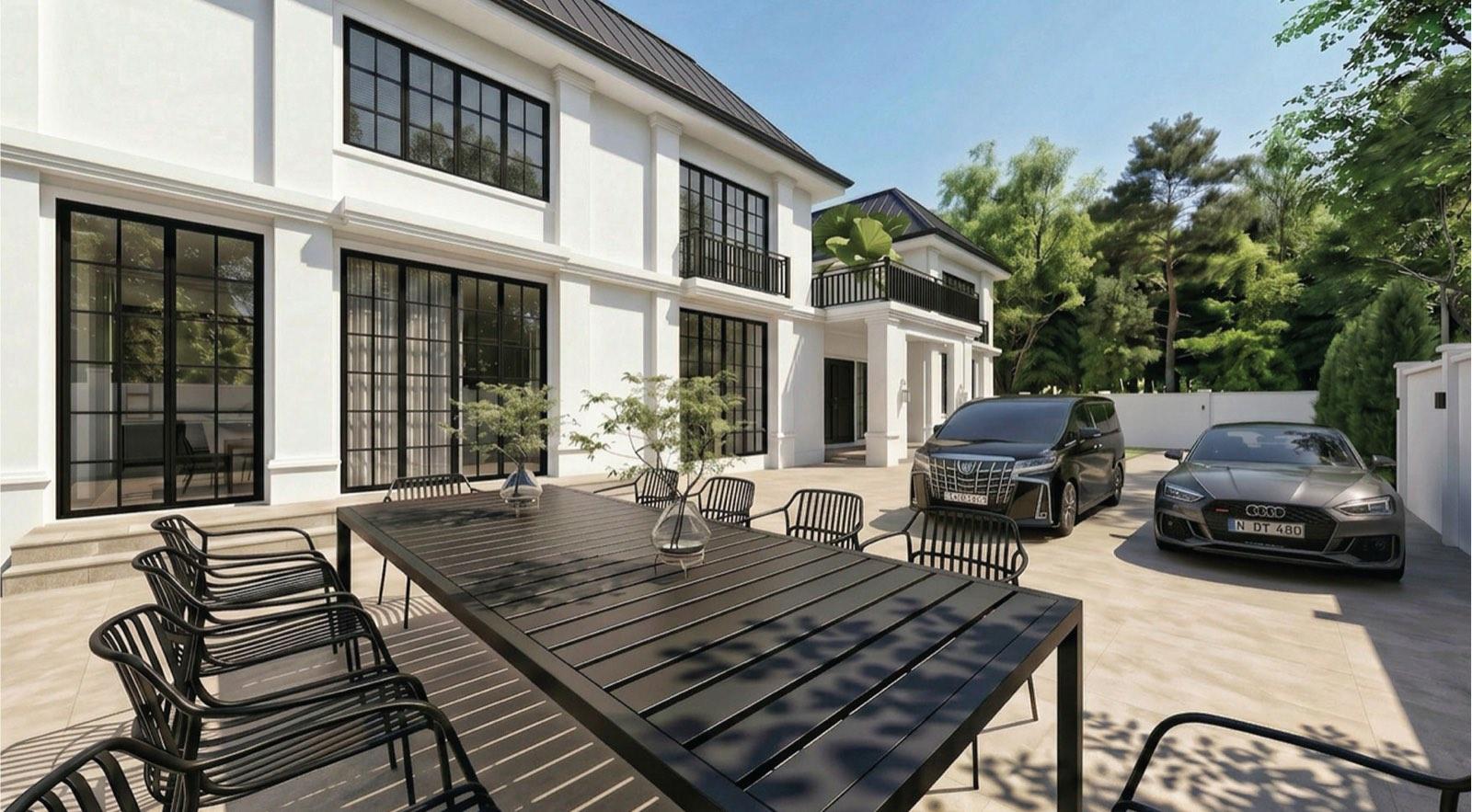 Long outdoor dining table on the driveway terrace of the KGSAAS villa in Shah Alam, black-framed glazing running along the house