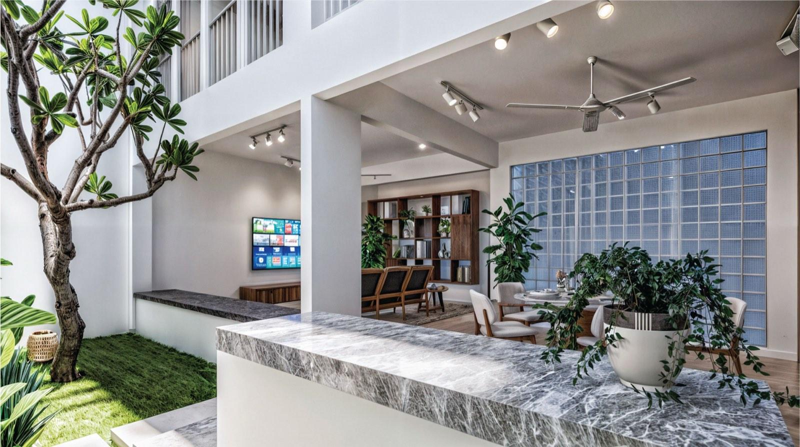 Grey marble counters in the double-volume core of the Kuala Lumpur terrace house, glass-block wall lighting the dining area