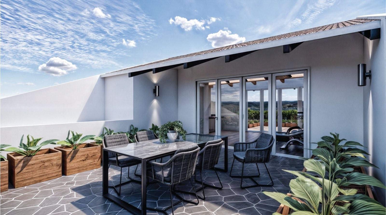 Roof terrace of the Kuala Lumpur terrace house, dining table in the foreground and the gym pavilion behind glazed doors